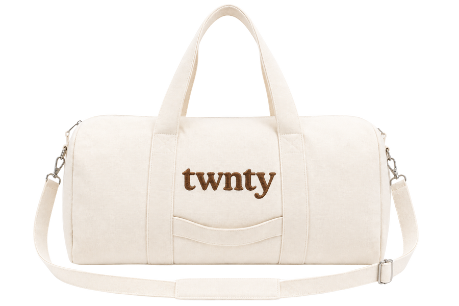 Natural canvas TWNTY tote bag with embroidered brown logo, top handles, front pocket, and adjustable shoulder strap.